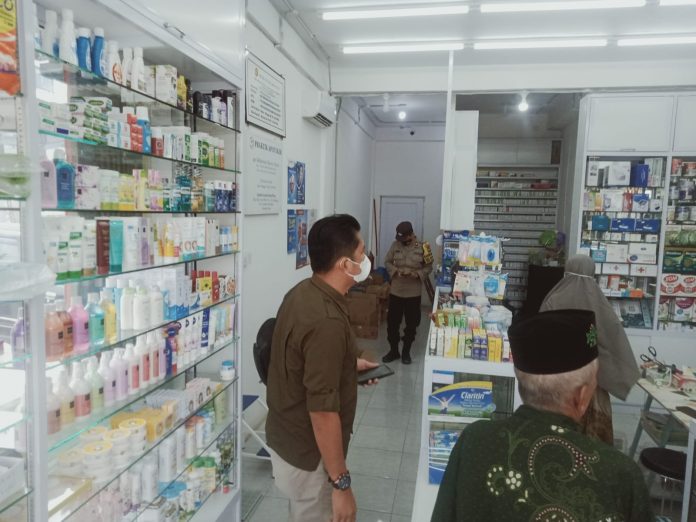 Anggota Opsnal dan Bhabinkamtibmas Kelurahan Mangsang Aipda Tomy Harles. (berseragam polisi) saat mengecek langsung ke apotek di Sebeduk, Jumat 21 Oktober 2022. (F : muhammad amin - batamtv.com)