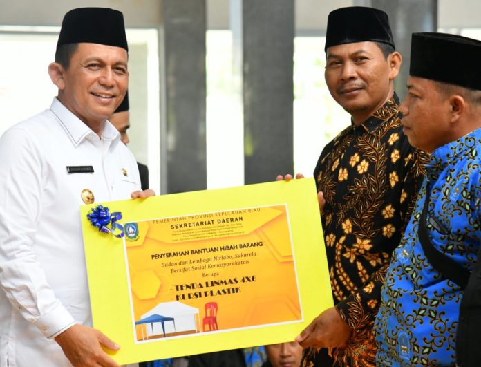 Gubernur Kepri Ansar Ahmad (kiri) menyerahkan secara simbolis bantuan   honorarium kepada para mubaligh, yang bertempat di Masjid Darussalam Perumahan KDA, Kota Batam, Kamis (1/12/2022).  Ansar Ahmad  juga melakukan  penyerahan bantuan hibah berupa barang dan kendaraan, kepada sejumlah yayasan. (Foto : Abyaqsa Ra)
