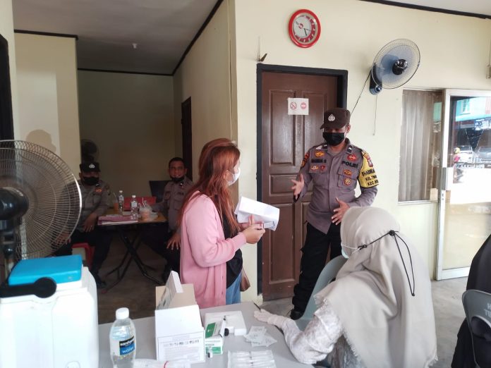 Bhabinkamtibmas Kelurahan Tiban Indah Polsek Sekupang Sekupang Aipda Manda S, saat memberikan arahan kepada salah satu warga yang akan ikut vaksinasi lanjutan. Vaksinasi dosis lanjutan (booster ini dilakukan di Halaman Kantor Pos Sekupang . (Foto : Abyaqsa Ra - batamtv.com)