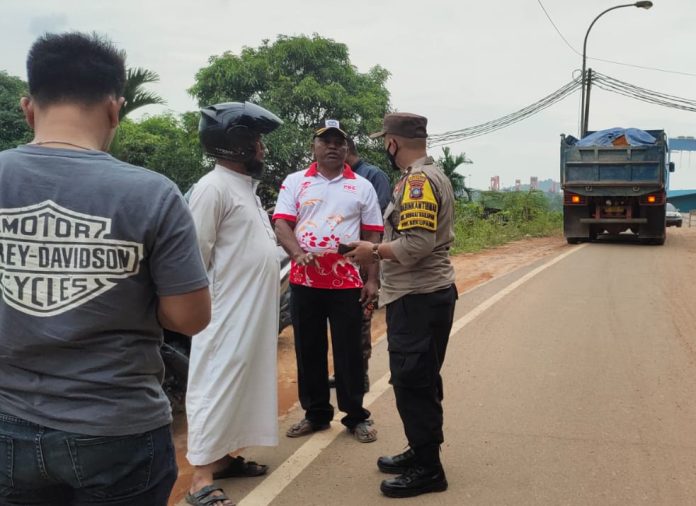 Bhabinkamtibmas (seragam polisi) Sei Harapan Polsek Sekupang Aipda Syefriadi, saat berada di lokasi dan mengajak warga dan pihak perusahaan untuk  bermediasi di Polsek Sekupang . Hasilnya,  pihak pemilik lahan yang diwakili  Ngatimin dan warga sudah dilakukan mediasi oleh Bhabinkamtibmas Sei Harapan Aipda Syefriadi dan pihak perusahaan berjanji akan segera membersihkan jalan. (Foto : Muhammad Amin - batamtv.com)