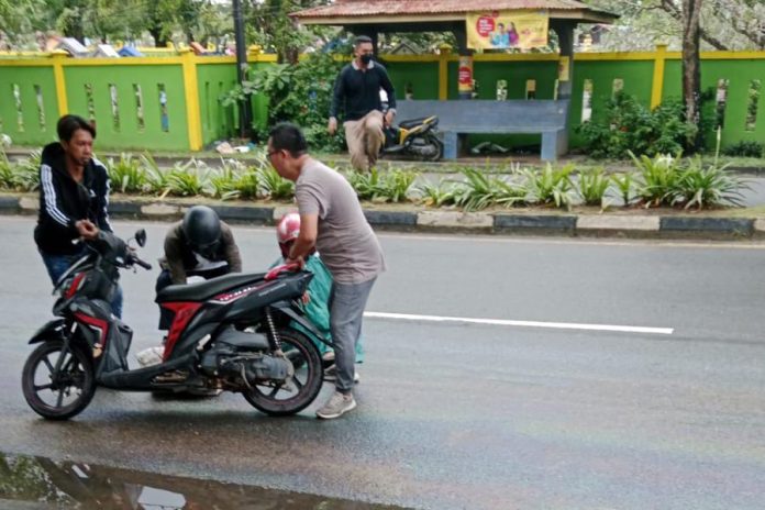 Seorang pengendara sepeda motor bernama Edwin (helm hitam) terjatuh akibat tumpahan minyak di Jalan DI Panjaitan KM 7 Tanjungpinang , Kepri , Selasa (13/12/2022). Korban menyebut, selain dirinya, korban lain terjatuh di sana lebih dari satu orang.  Korban mengatakan tidak mengetahui pasti cairan apa, namun dari bentuknya seperti oli atau solar  warnanya hitam. (Foto : Dwi Susilo - batamtv.com)