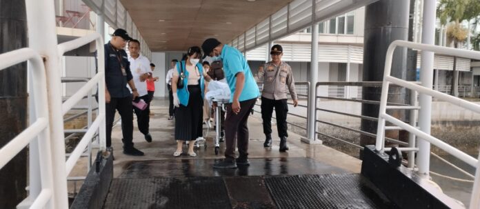 Dikawal anggota Polsek KKP Kota Batam , sejumlah tenaga medis mengevakasi seorang pasien gawat darurat ke kapal yang akan menyeberang ke Malaysia, Senin (27/3/2023). ( Foto : muhammad amin - batamtv.com)