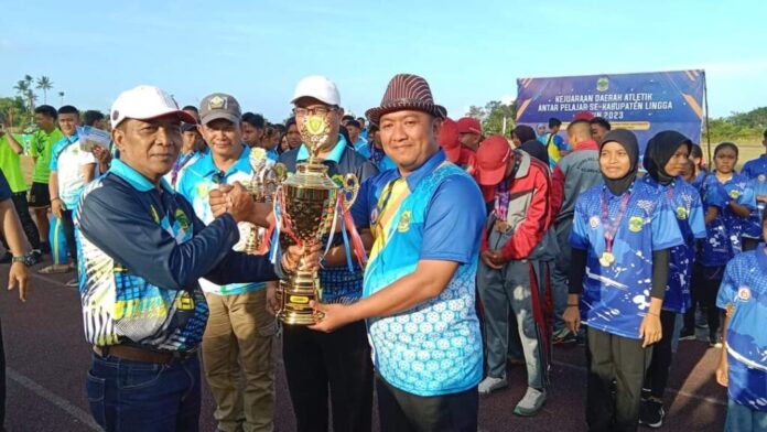 Asisten II Setdakab Lingga, Zainal Abidin (kiri) menyerahkan piala Juara Umum kepada Ketua Korwil Singkep Barat Dan Kepulauan Polsek, Agus Kurniawan  di Lapangan Lintas Atletik Kecamatan Singkep Pesisir, Kamis (16/3/2023). (Foto : abdi perdana - batamtv.com)