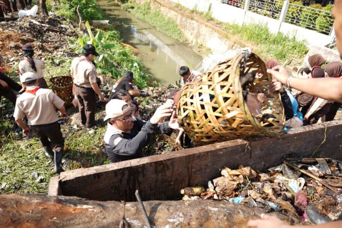 Ketua Kwartir Cabang Pramuka Kota Batam, Jefridin (pegang kranjang sampah) saat ikutserta gotong oyong membersikan sampah di parit. (Foto : muhammad amin - batamtv.com)