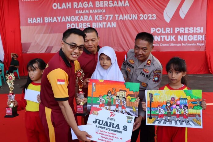 Kapolres Bintan, AKBP Riky Iswoyo (kiri) menyerahkan hadiah kepada Kepala Sekolah Dasar yang telah mengirimkan anak didiknya untuk mengikuti perlombaan mewarnai tersebut. (Foto : abdi perdana - batamtv.com)