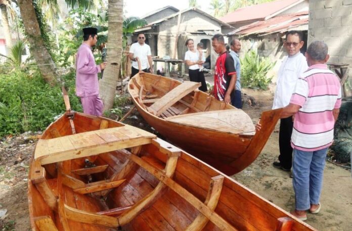 Wakil Ketua II DPRD Karimun, Kepulauan Riau (Kepri)  Rasno, SE, MSi (baju putih, kedua dari kanan) saat menyalurkan bantuan berupa sampan dan mesin kepada Kelompok Nelayan di Pulau Kundur, Minggu (9/7/2023).  (Foto : abdi perdana - batamtv.com)