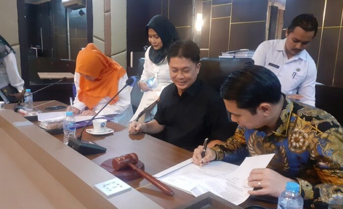 Ketua Pnitia Pemilihan Wakil Bupati Bintan sisa masa jabatan 2021-2024, Mirwan (kemeja hitam) menyaksikan langsung  Ahdi Muqsith dan Dhenok Puspita Sari menandatangani berkas pendaftaran dan penyerahan syarat administrasi Cawabup Bintan, Rabu (12/7/2023) (Foto : abdi perdana - batamtv.com )