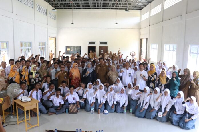 Ketua TP-PKK Provinsi Kepulauan Riau Hj. Dewi Kumalasari Ansar menyerahkan Akta Notaris Koperasi Sekolah kepada SMKN 1 Gunung Kijang, Bintan, Senin (7/8) . Dewi Ansar sat bersama siswa dan dewan guru. (Foto: aabdi perdana - batamtv.com)