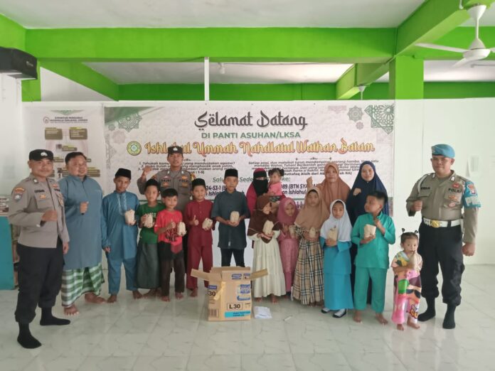 Panit Binmas Polsek Sekupang Aiptu Luqman bersama Bhabinkamtibmas Patam Lestari Bripka Fajeri Hamsyah dan Kanit Provos Bripka Irwan Taufik membagikan nasi kotak ke Panti Asuhan yang diterima langsung oleh pengurus panti dan anak-anak yatim piatu binaannya. (Foto : muhammad amin - batamtv.com)