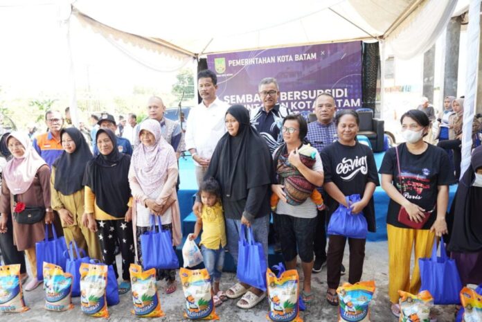 Walikota Batam HM Rudi (baju putih di belakang) saat pebagian sebanyak 1.600 paket sembako subsidi dibagikan ke masyarakat di Kelurahan Tanjunguncang dan Kelurahan Bukit Tempayan, Kecamatan Batuaji,  Kamis (7/12/2023). (Foto : abyaqsa ramadan - batamtv.com -)