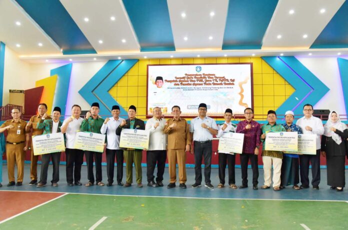 Gubernur Kepri Ansar Ahmad (tengah seragam cokelat) menyerahkan bantuan terhadap Guru Pendidikan Keagamaan Non Formal, Guru TK, Guru PAUD, Guru RA, Penyuluh Agama Non ASN, dan juga Pemuka Agama Tetap Pada Rumah Ibadah, mendapatkan bantuan untuk Tahun 2023 di Kota Batam Senin, (11/12/2023). (Foto : muhammad amin - batamtv.com)